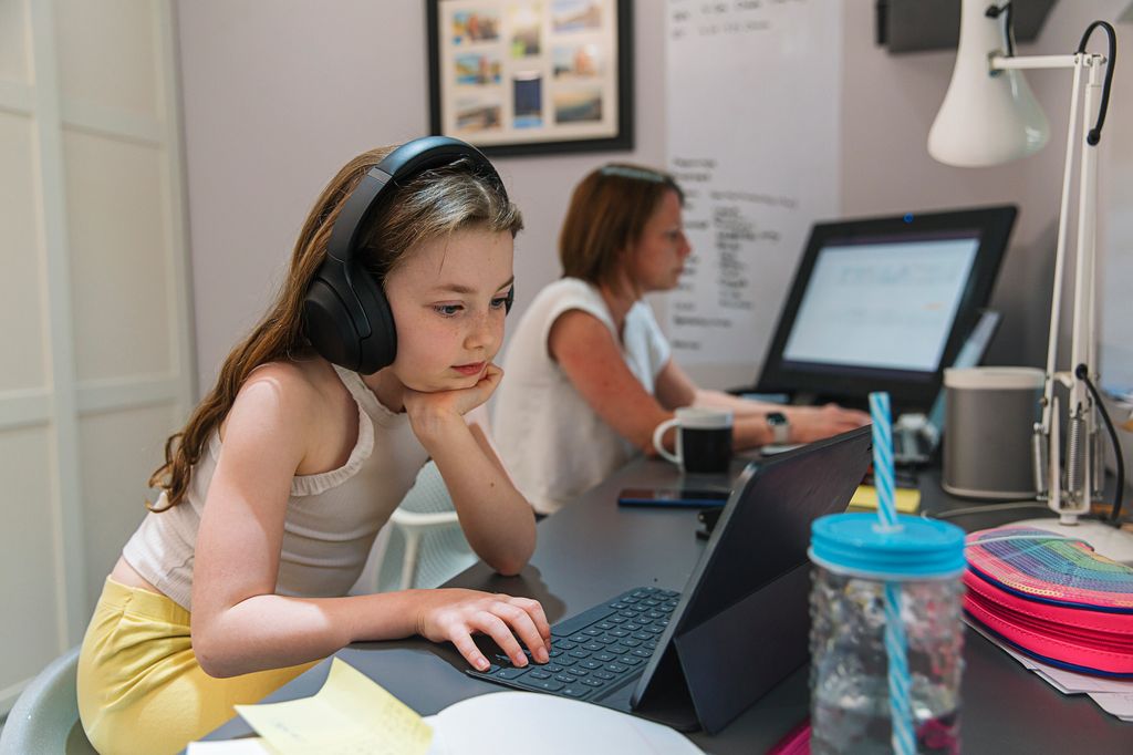 Young girl remote schooling in study with mum