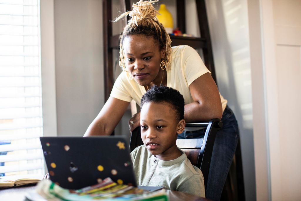 Mother helping son on laptop at home