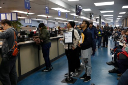 Elias Dubaie ( center l to r) of San Francisco and Kahlai Pratt of San Francisco watch a sign board while they wait in line to apply for the Real ID at the DMV on Fell Street  on Friday, January 24, 2020 in San Francisco, Calif. (Photo By Lea Suzuki/The San Francisco Chronicle via Getty Images)