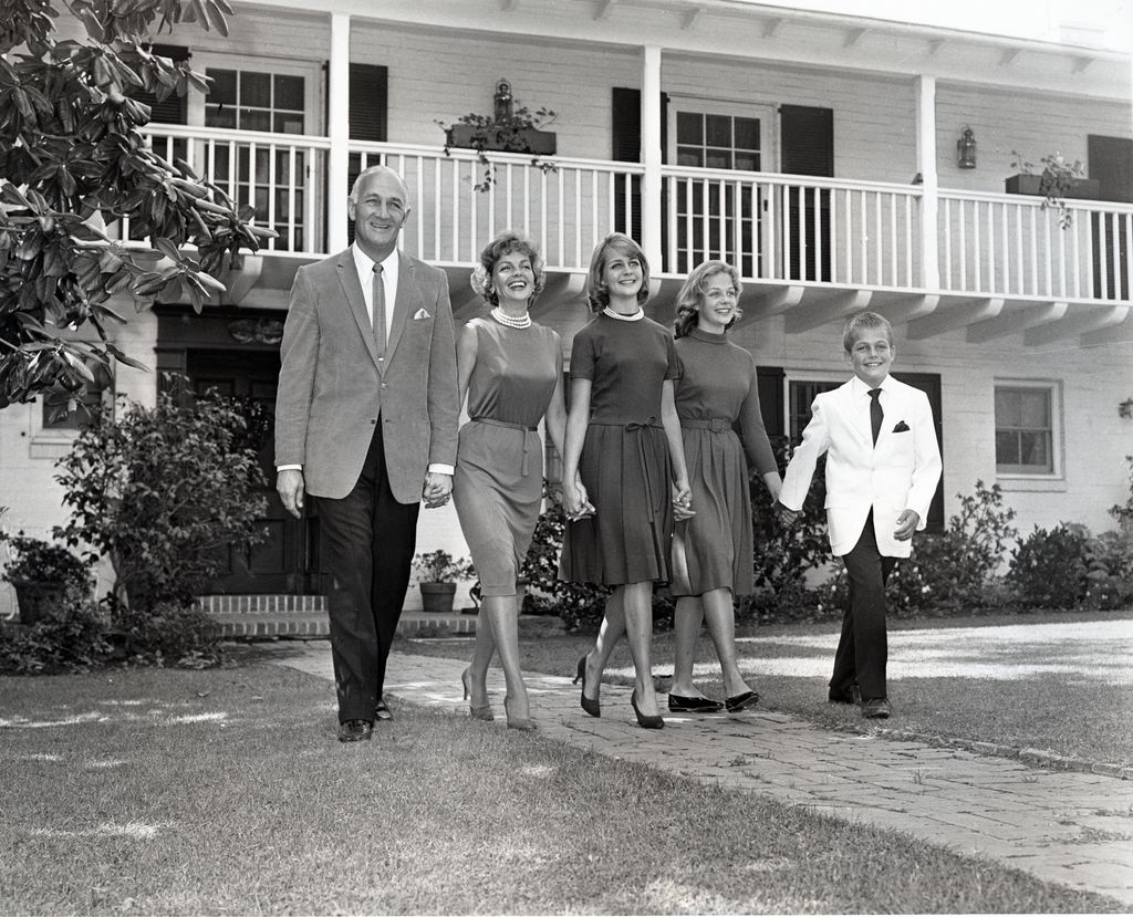 Tom Harmon family walking in front of their house holding hands. Thomas Dudley Harmon, sometimes known by the nickname "Old 98", was an American football player, military pilot, actor, and sports broadcaster. Wife, Elyse Knox/Actress, Daughters Kristen (Nelson, Rickey), Kelley and  famous actor son, Mark Harmon.  Circa 1963