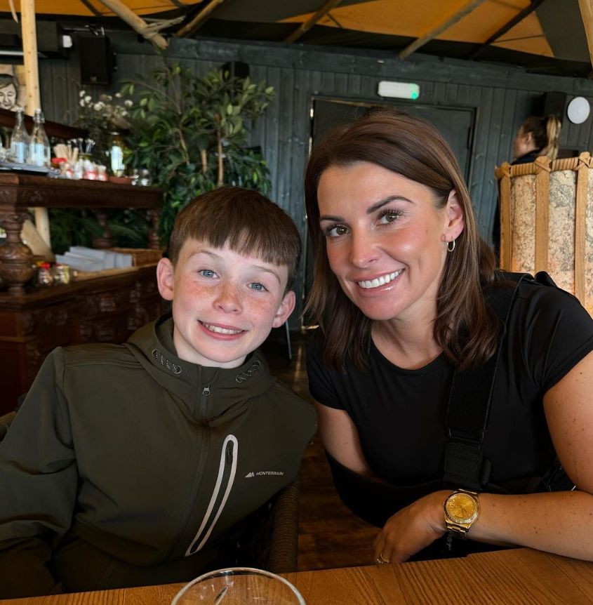 Coleen Rooney and her son smiling at a table