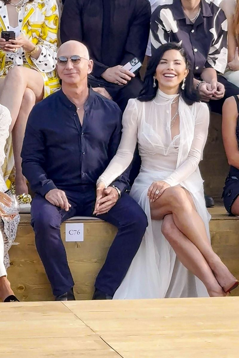 Amazon founder Jeff Bezos and helicopter pilot and author Lauren Sanchez look in love as they hold hands, sitting in the front row at the Dolce & Gabbana fashion show in Sardinia. 
