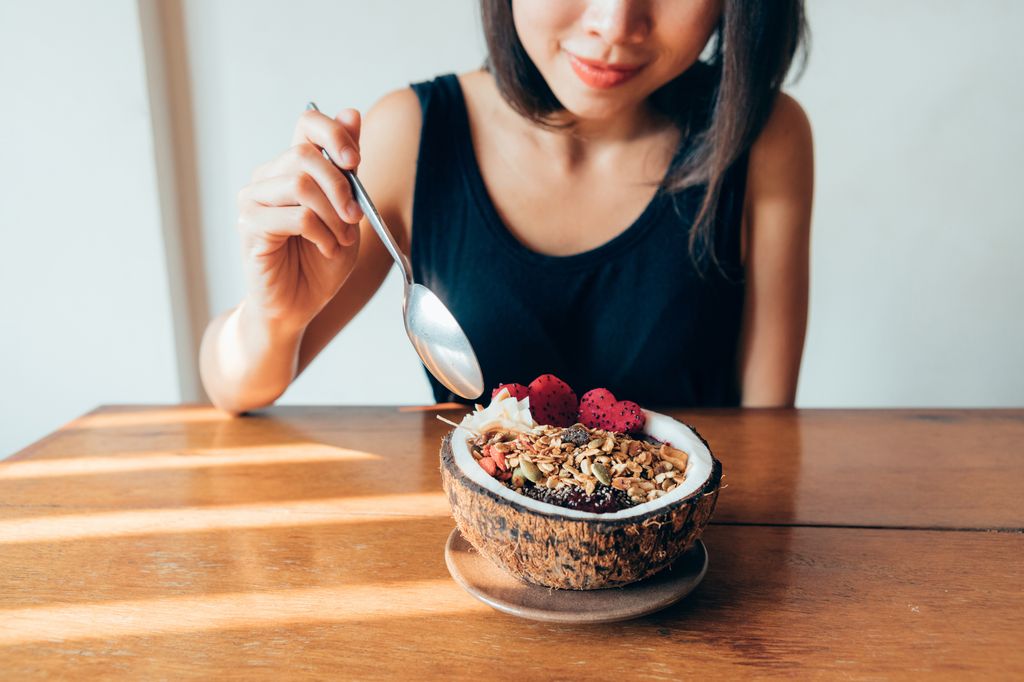 Close-up shot of smiling young woman eating healthy breakfast.