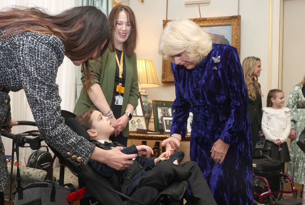 Queen Camilla speaks with a young boy as she welcomes children and families supported by Helen & Douglas House and Roald Dahl's Marvellous Children's Charity