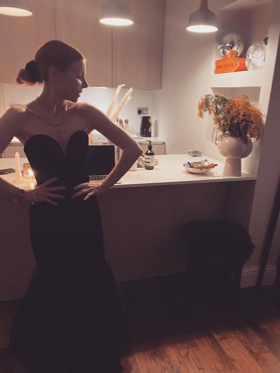 Stacey Dooley posing in a kitchen in a black dress