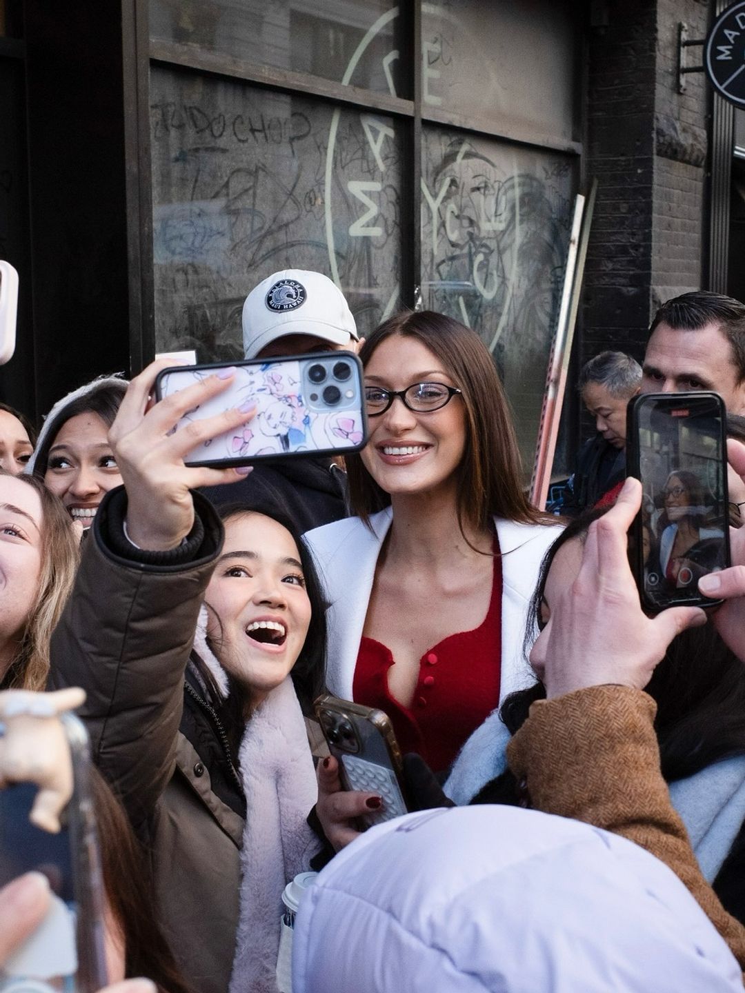 Bella Hadid poses with some fans outside of her NYC popup