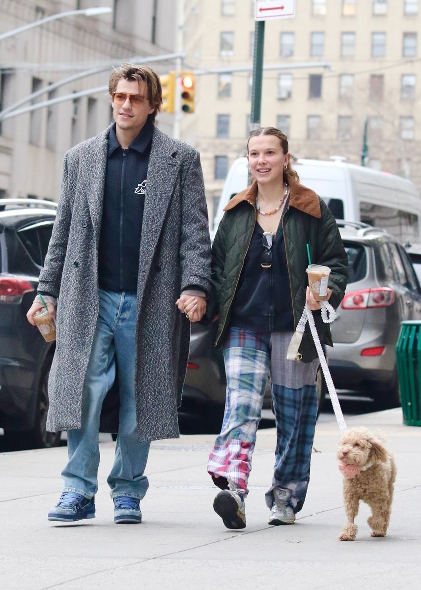 Millie Bobby Brown and her husband Jake Bongiovi share smiles and hold hands during a romantic walk in Downtown Manhattan with their dog Winnie. 