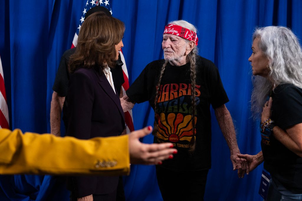 Kamala Harris speaks with US Singer Willie Nelson (C) and his wife Annie D'Angelo backstage