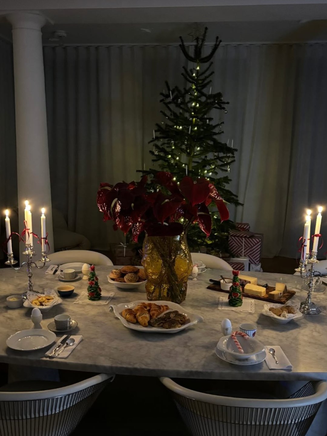 A marble table featured poinsettias, candy-cane candles, and pastries. Soft lighting and a minimalist tree created cozy elegance.