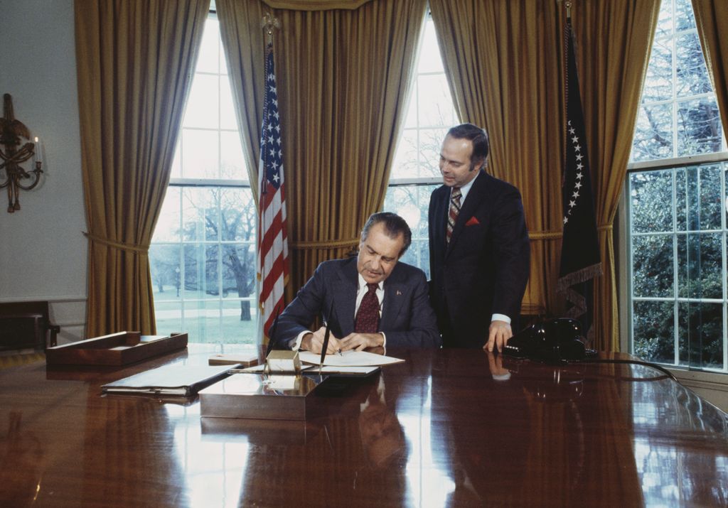 President Richard Nixon (1913 - 1994) signs the 'Daylight Saving' Act at the White House In Washington on December 15th, 1973. He is watched by Representative Normal Lent who pushed the bill through the House