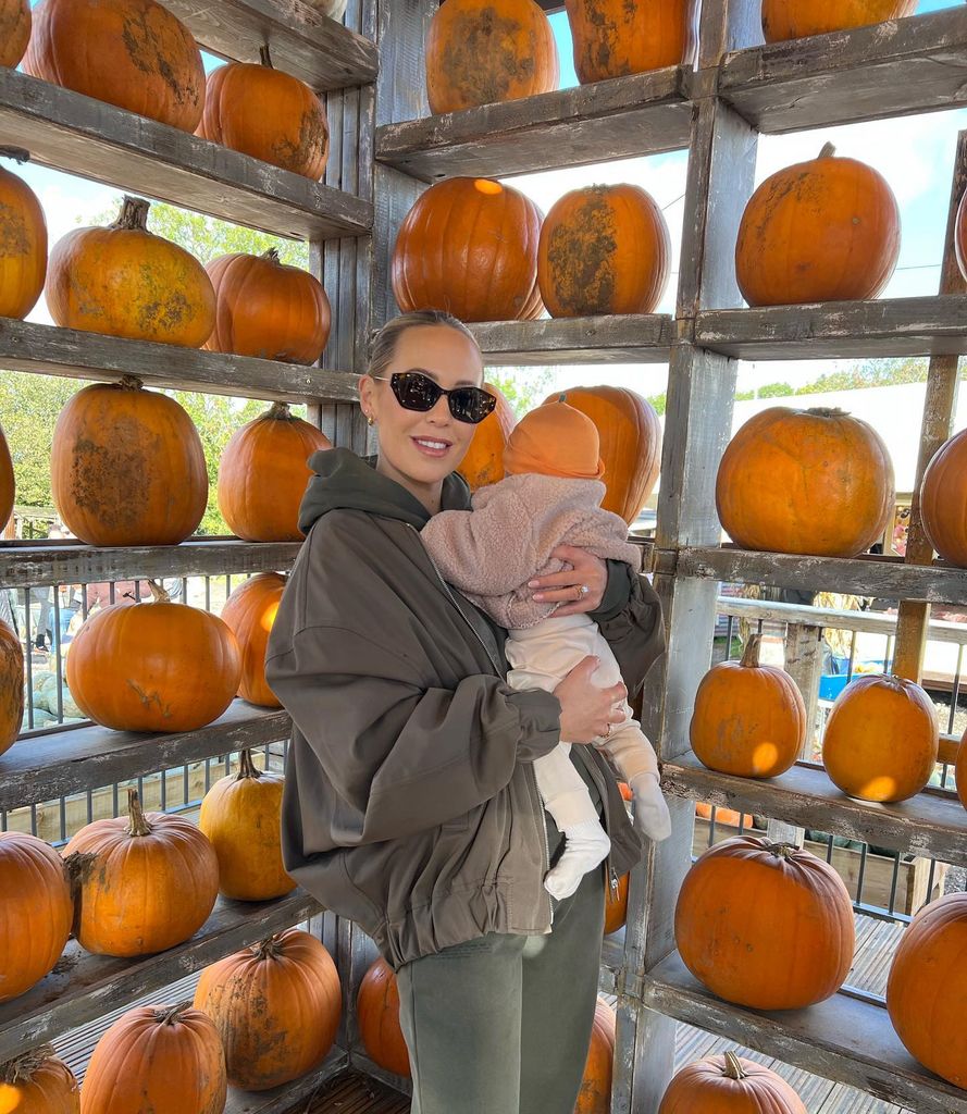 kate holding baby with pumpkin wall