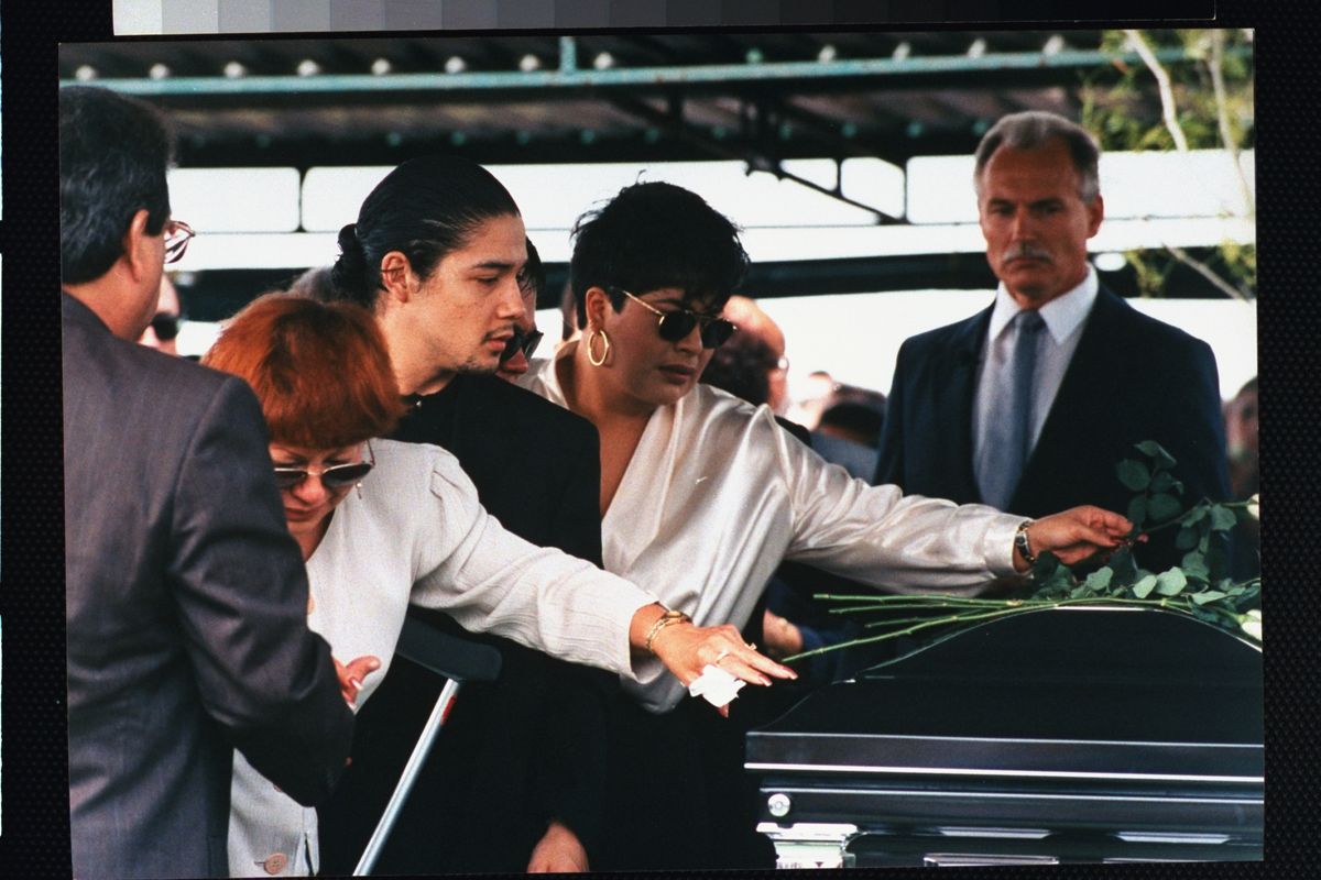 Family of tejano singer Selena who was killed by her former fan club pres. Yolanda Saldivar: mother Marcela Quintanilla (2L), husband Chris Perez (3L) & sister Suzette (2R) laying roses atop casket at her funeral.    (Photo by Barbara Laing/Getty Images)