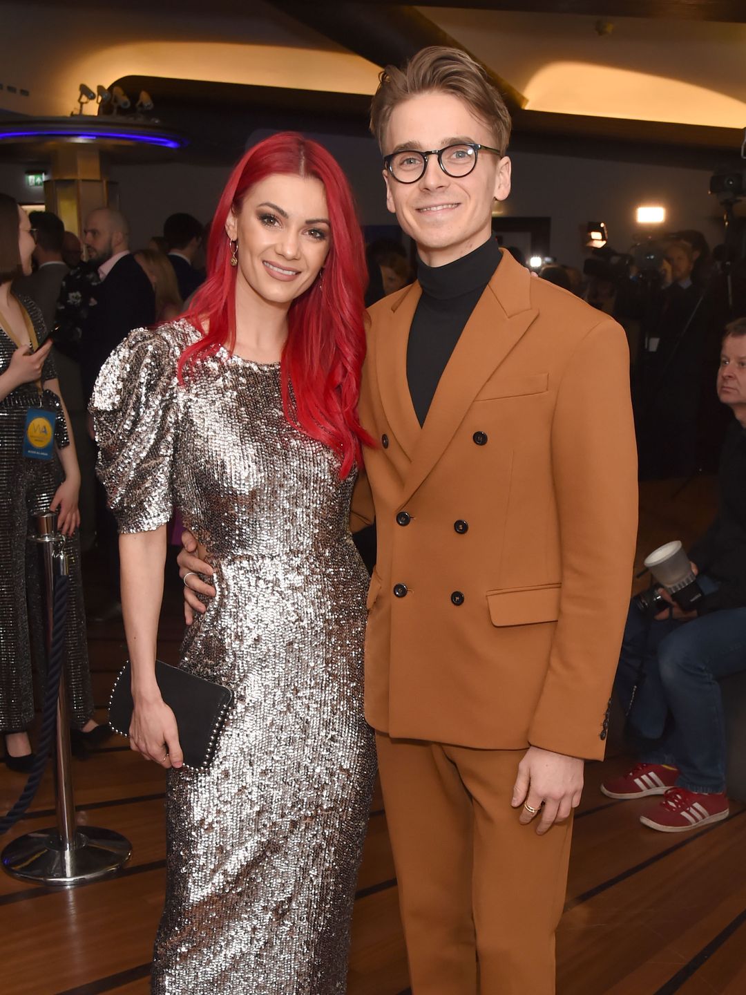 Dianne Buswell in a silver dress standing with Joe Sugg in a brown suit