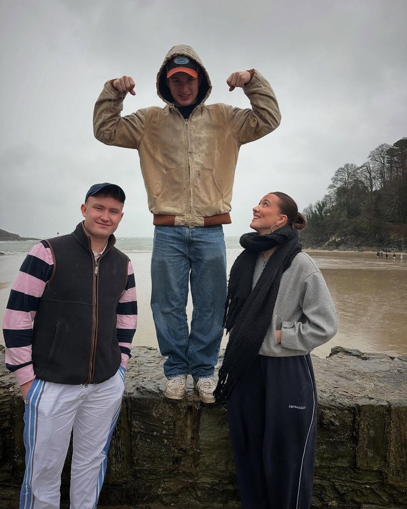 three teenagers posing beside sea 