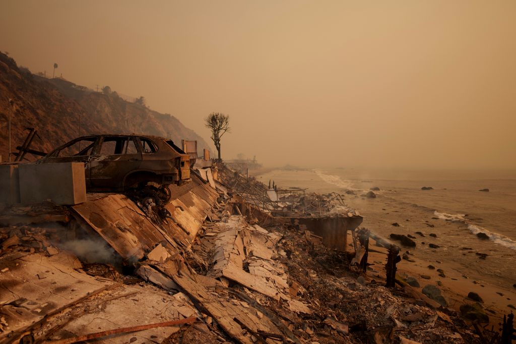 A burned car sits next to the remains of a home destroyed during the Palisades Fire on January 8, 2025 in Malibu, California