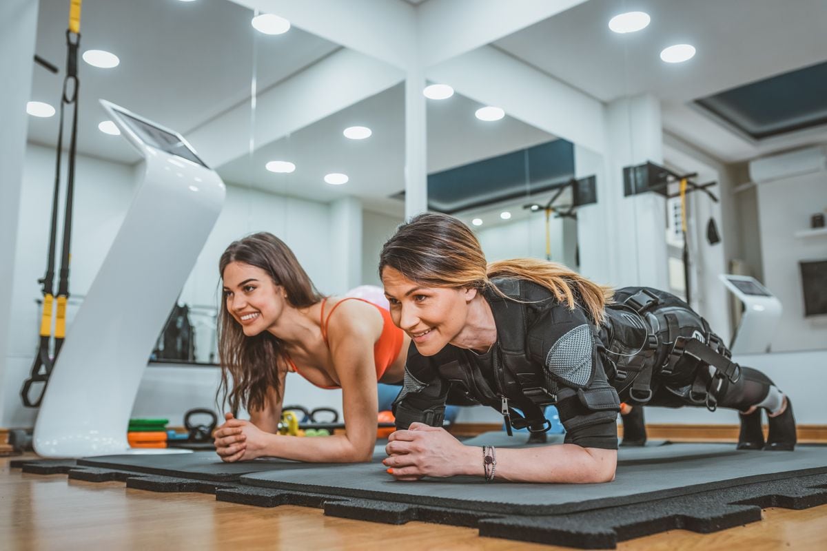 Two women practice electro stimulation of muscles. 