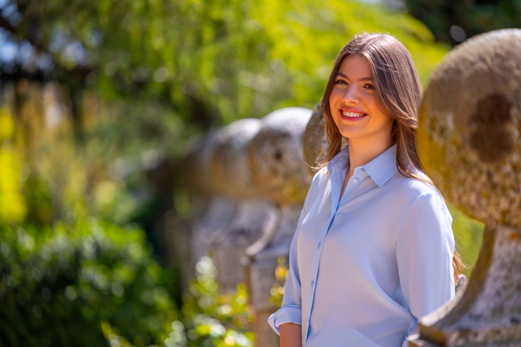 A girl wearing a blue shirt smiling in a garden