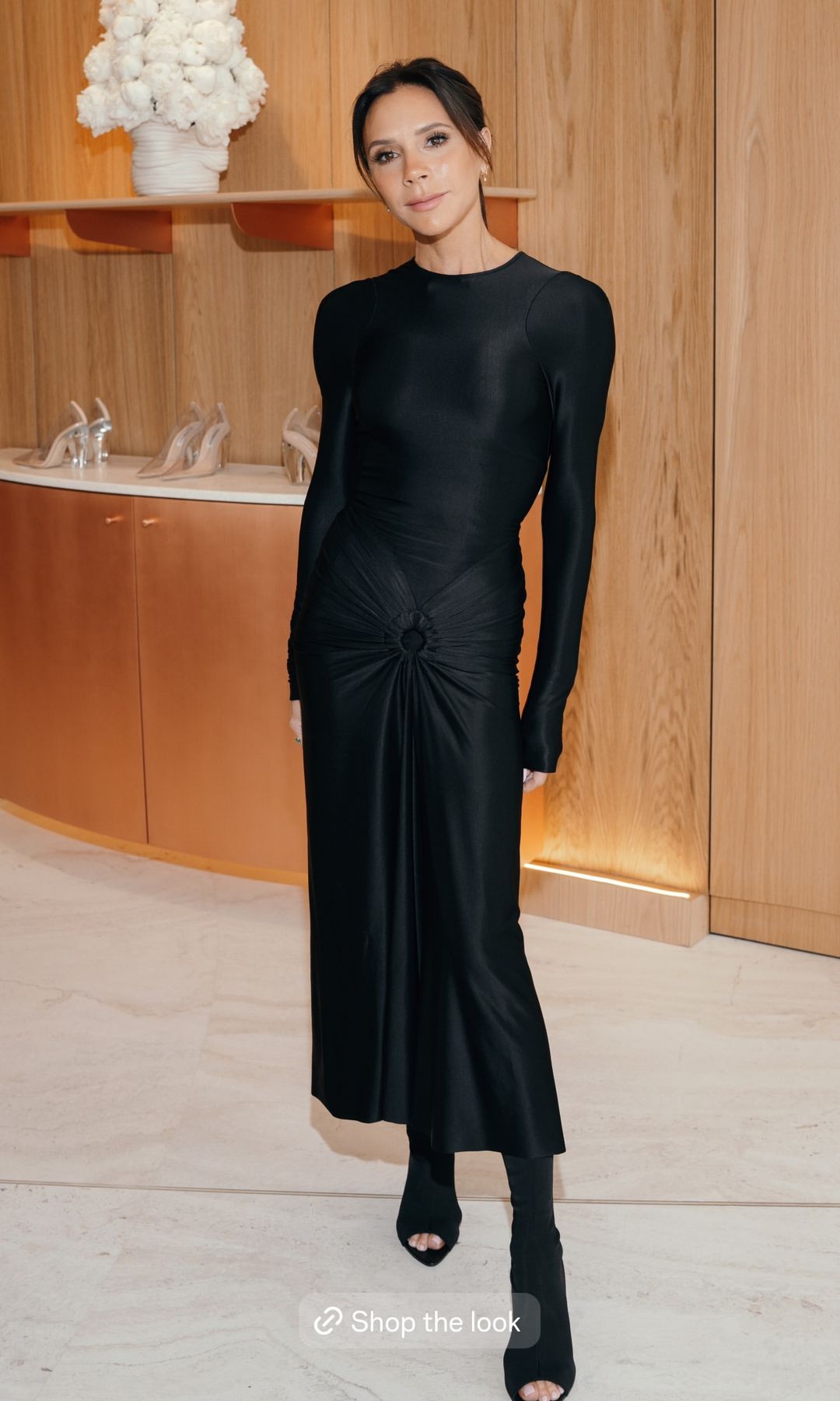 Victoria Beckham poses for a photo in a black skin-tight dress and peep-toe shoes