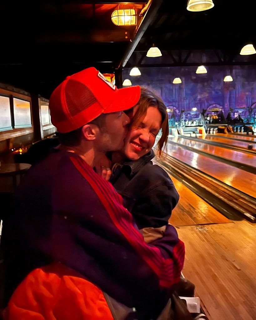Zach Gilford kisses wife Kiele Sanchez on the cheek in a bowling alley