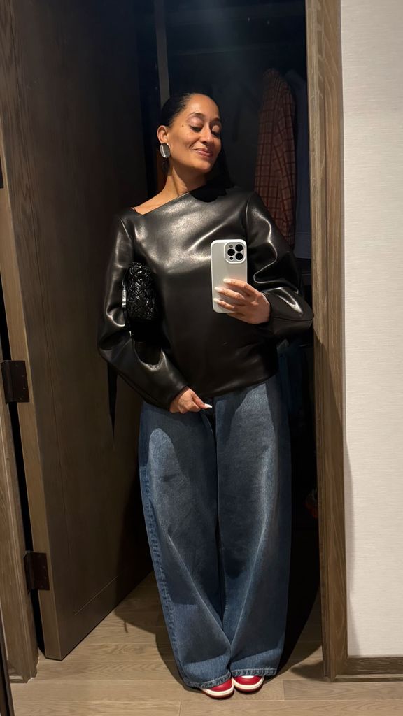 Tracee Ellis Ross takes a photo of her black leather dress styled with jeans for her Instagram Stories