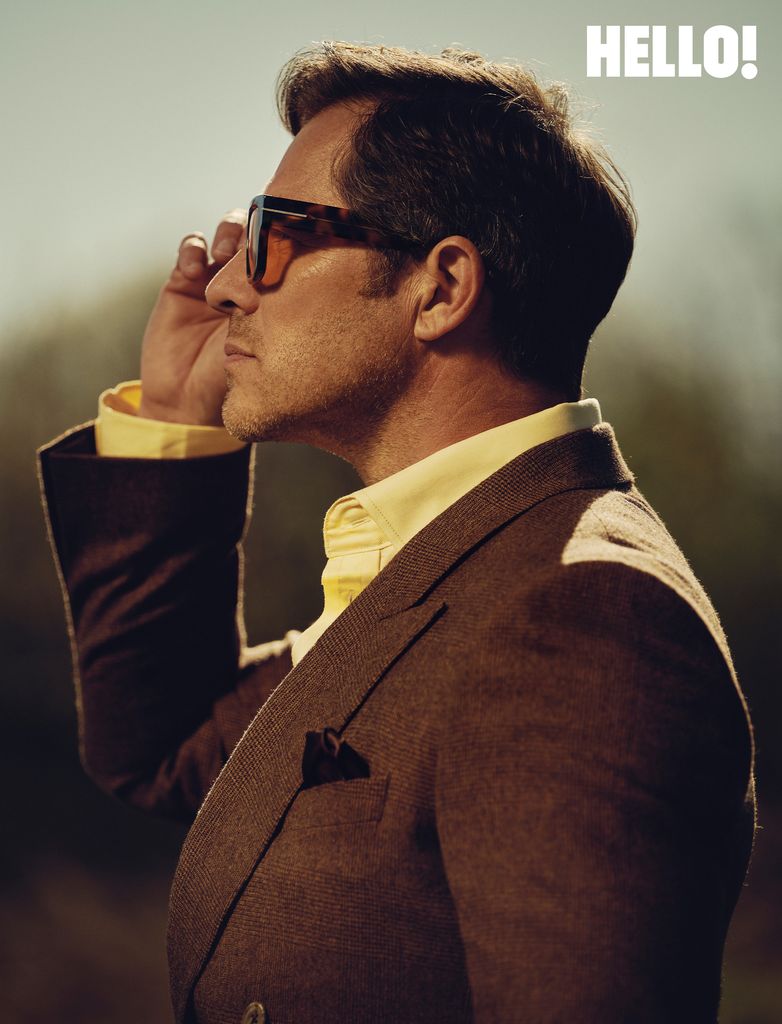 A man looking at the sun whilst touching his sunglasses