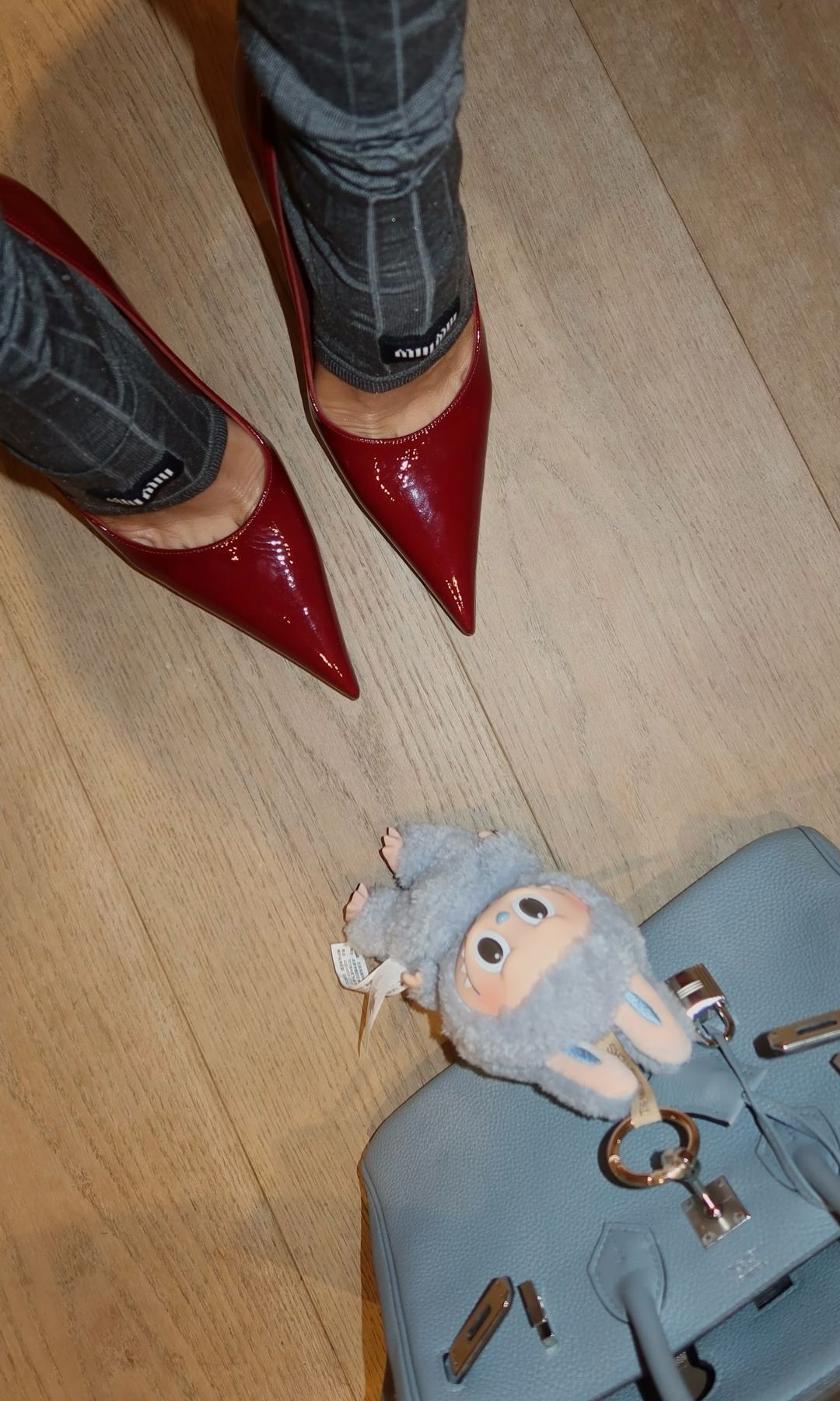 A closer look at Olivia's accessories of choice - red heels, grey ankle warmers and blue handbag complete with charm