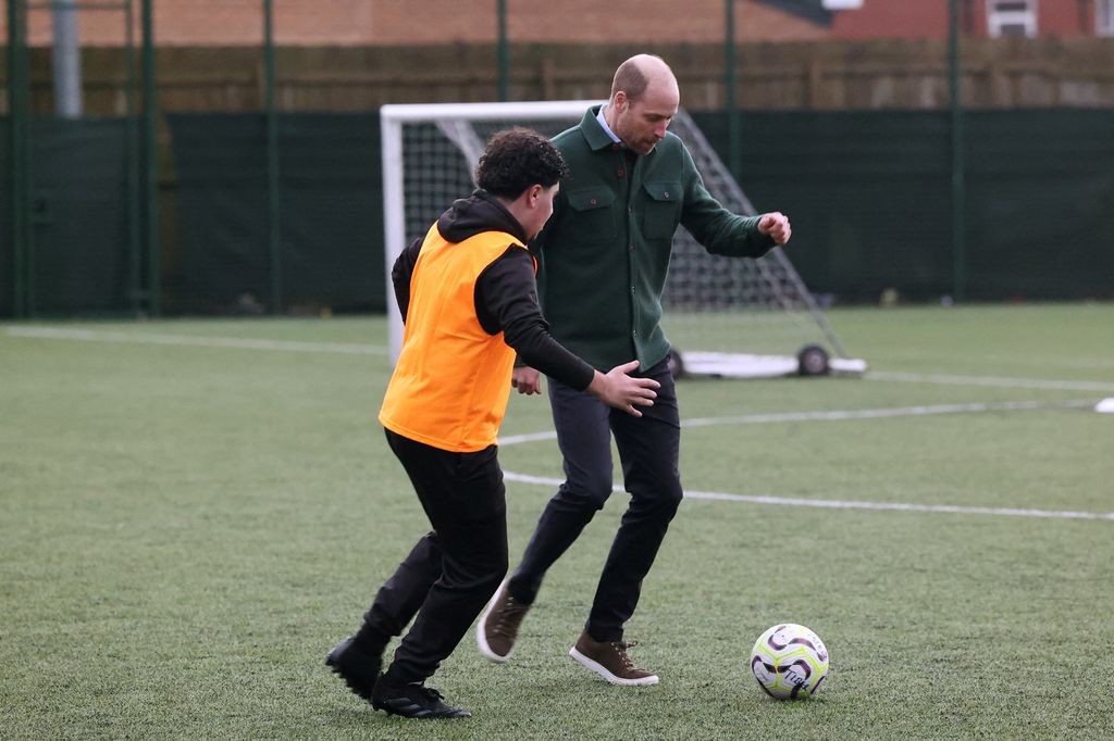 Prince William playing football with a young man in an orange vest