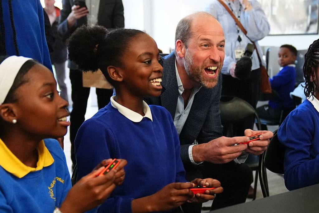 Prince William, Prince of Wales reacts as he plays a computer game with school children         