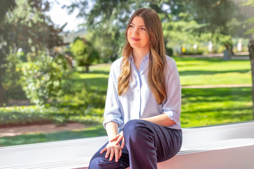 A girl with long hair looking towards the side whilst sitting