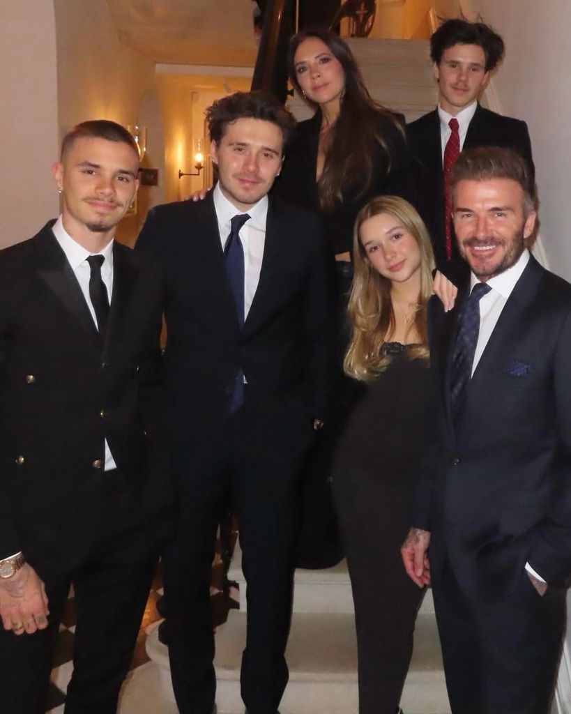 David and Victoria Beckham with their four children standing on the stairs in their home smiling for a photo