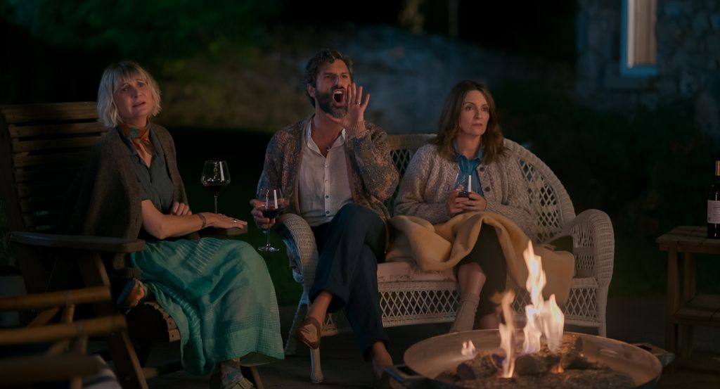 three friends sitting around outdoor fireplace