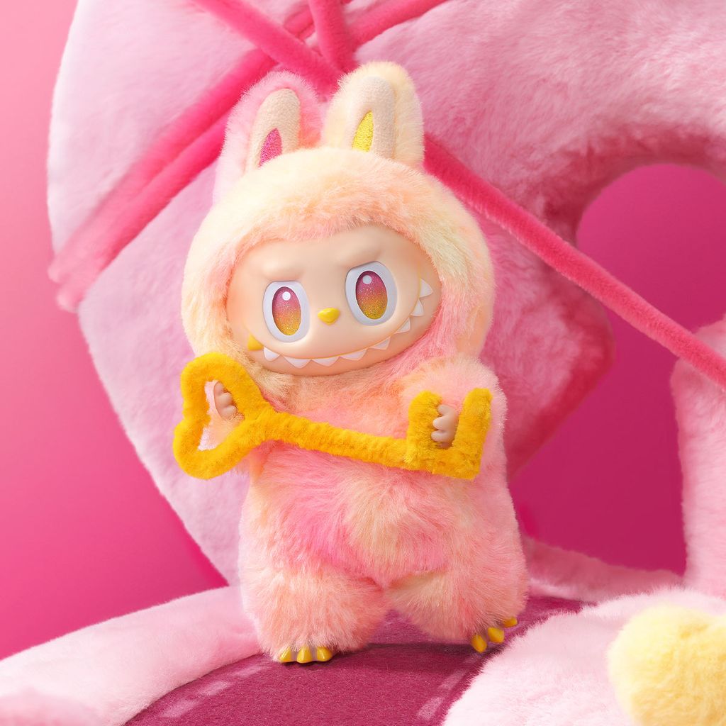 A pink Labubu photographed infront of a pink backdrop