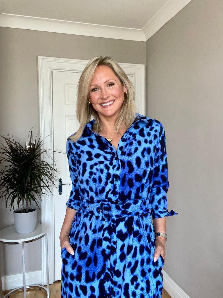 Lady smiling in a blue leopard print dress at home