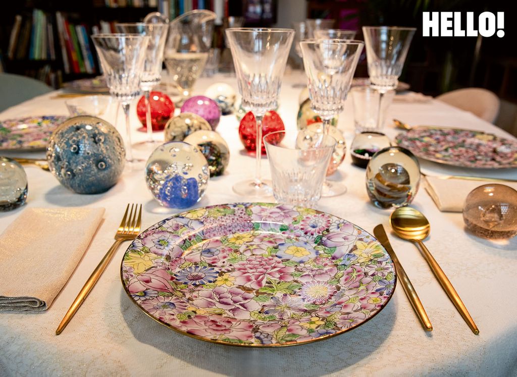  The dining table with glasses, gold cutlery and floral plates neatly arranged 
