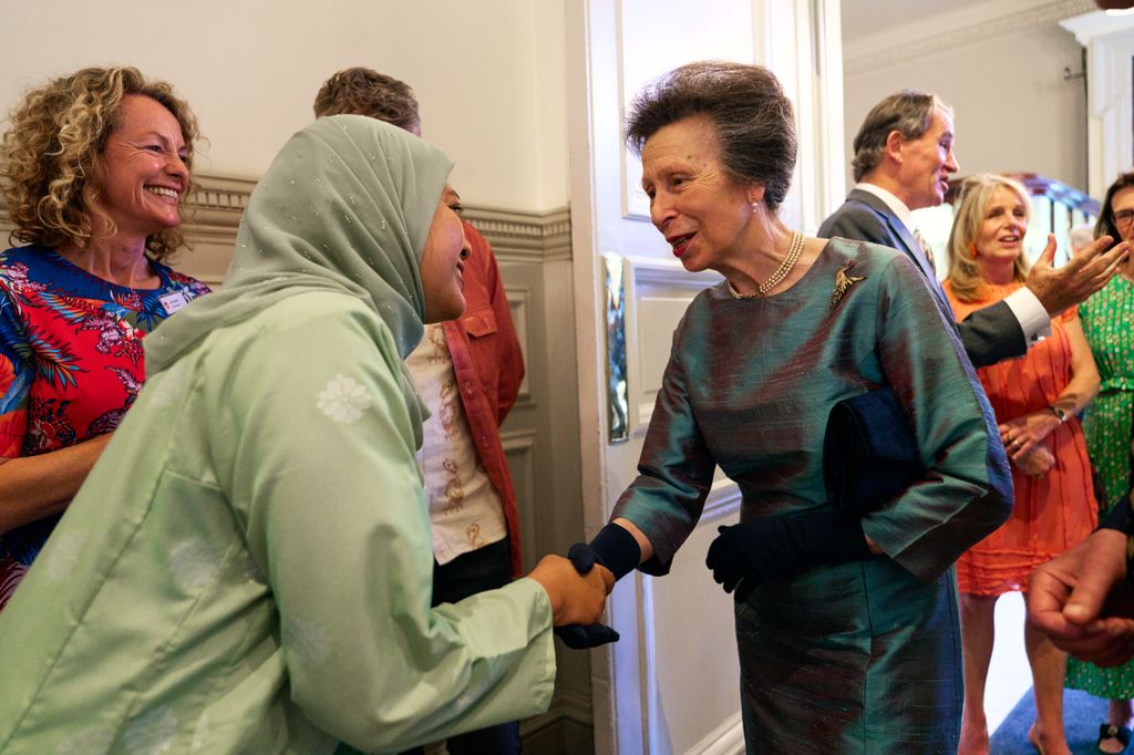 Princess Anne shaking hands with a woman while wearing gloves