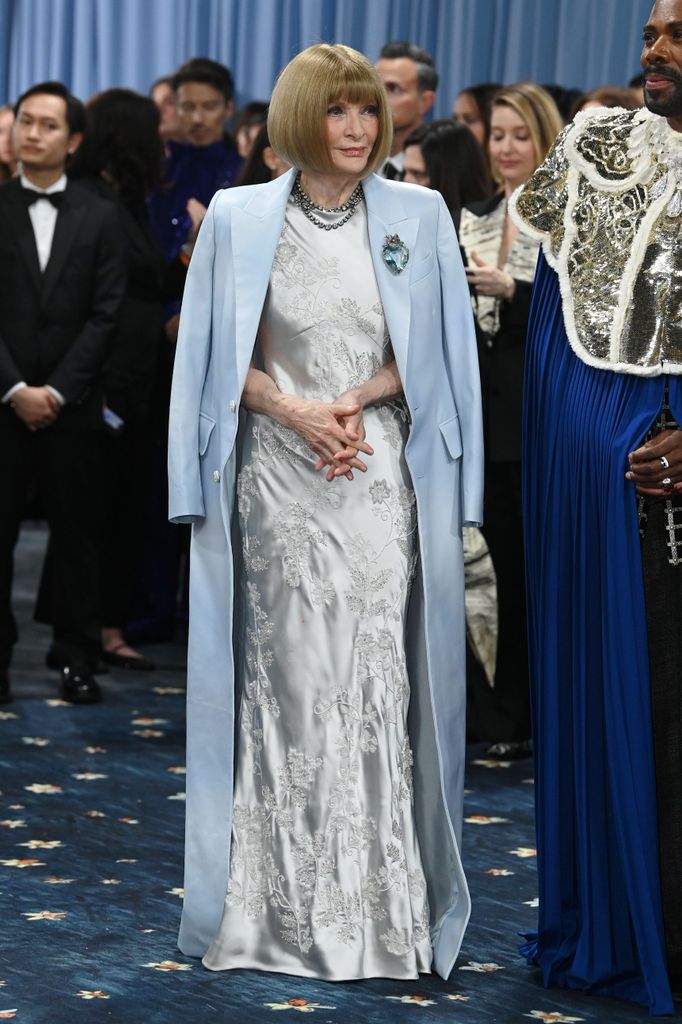 Anna Wintour wears an icy blue silk dress and a long blue coat teamed with several beaded necklaces
