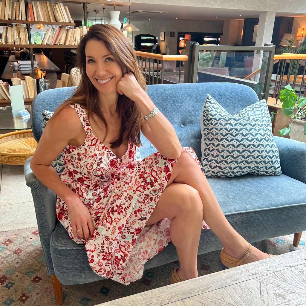 Woman sitting on a soft blue sofa wearing a floral midi dress