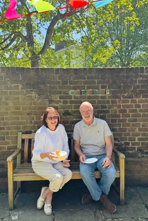 Two elderly people sitting on a bench with slices of cake