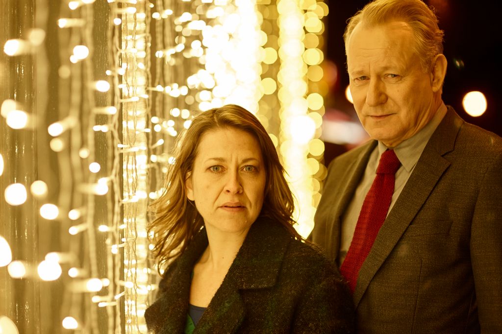 woman and man standing next to wall of fairy lights