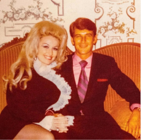 Dolly Parton sat next to Carl Dean smiling 