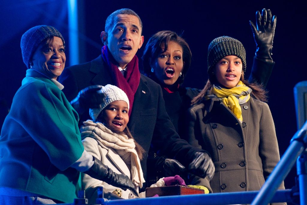 US President Barack Obama, joined by his family including First Lady Michelle Obama, daughters Sasha and Malia, and mother-in-law Marian Robinson, react as they push a button to light the National Christmas Tree during a ceremony on the Ellipse near the White House in Washington, DC, December 9, 2010.