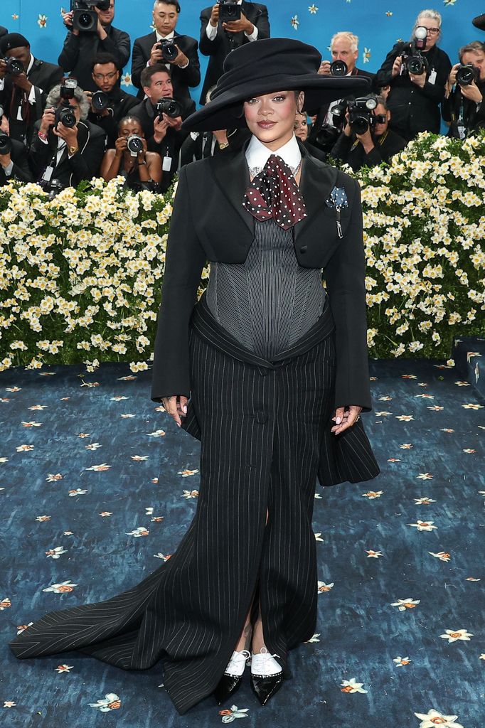 Rihanna wears a black pinstripe skirt, micro blazer and hat