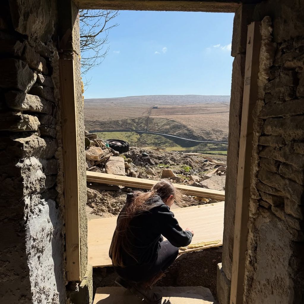 Amanda Owen's daughter in a doorway with countryside view in the background