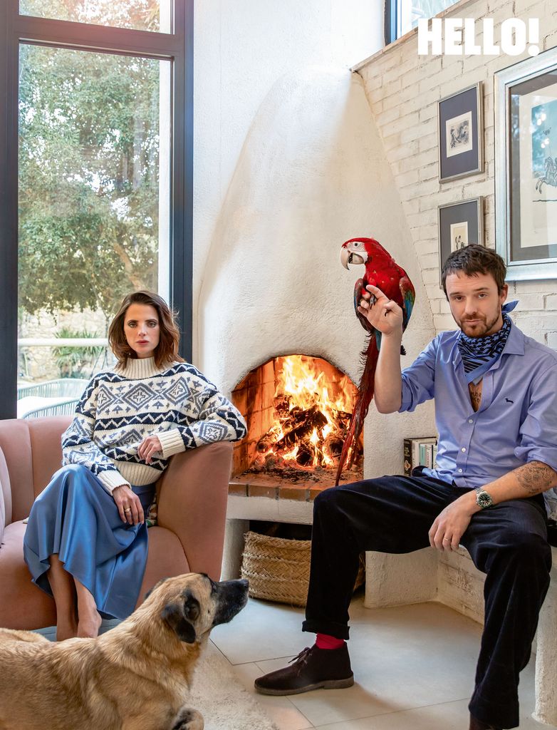 In their living room Aldo is sat holding a parrot and Macarena posing on a chair with a dog next to her