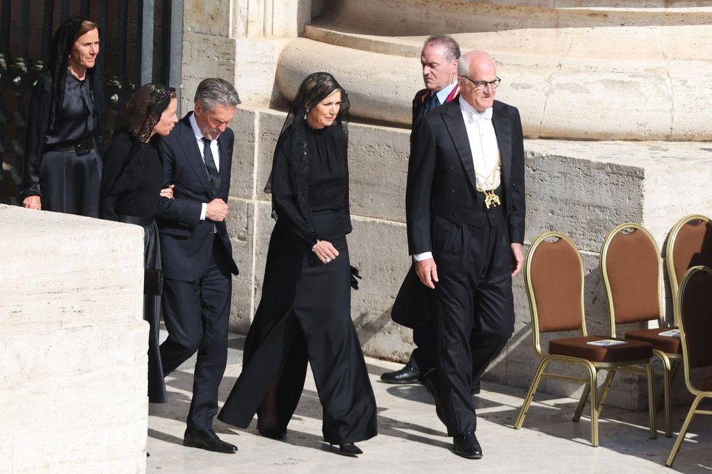 Queen Maxima walking in group of men in black outfit