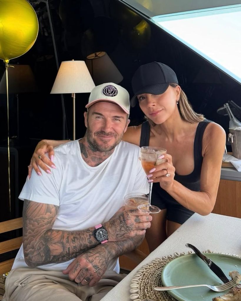 David and Victoria Beckham hold up drinks while sitting on a boat near their Miami home