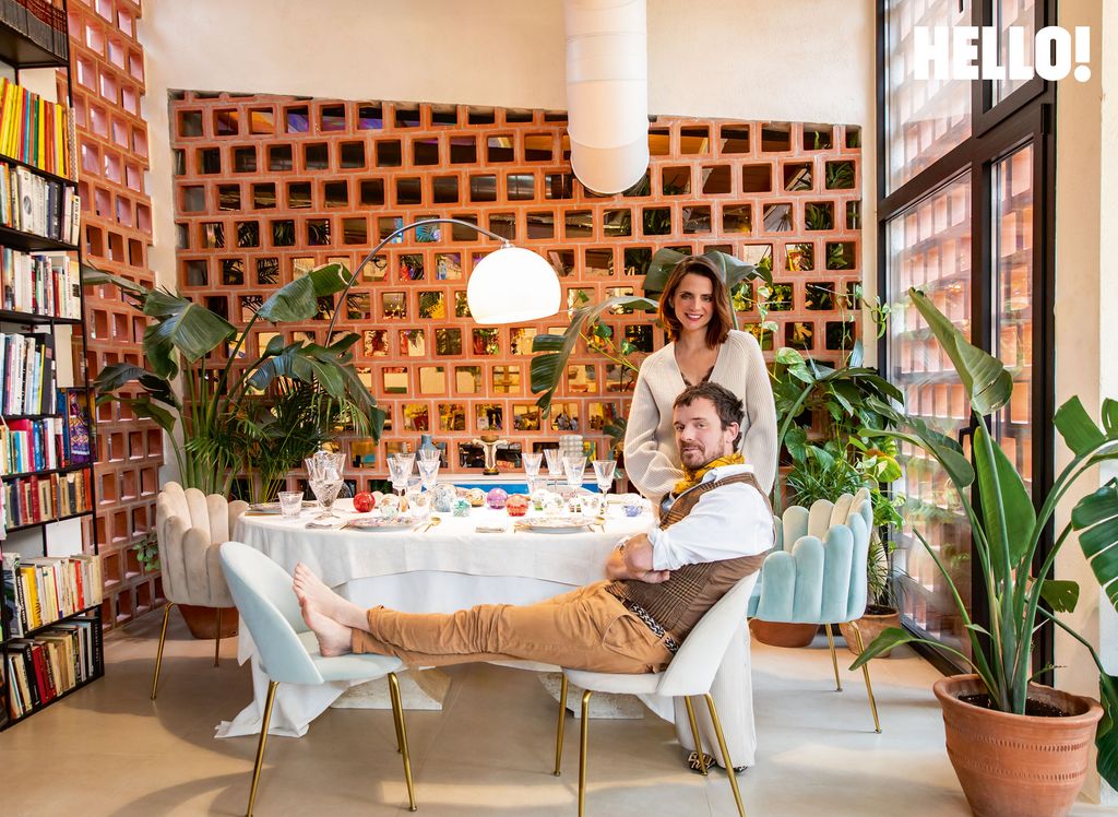 The couple pose next to their laid out dining table 