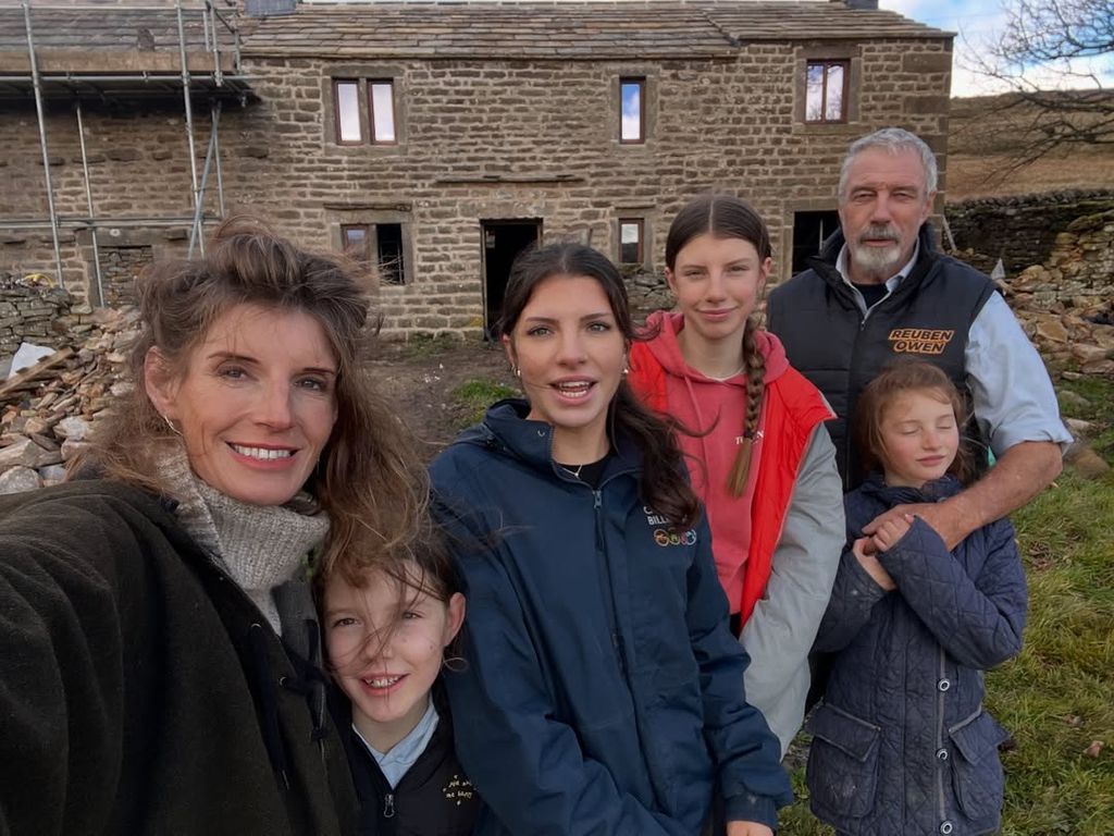 Amanda Owen with four of her children and ex-husband Clive posing for a selfie outside farmhouse