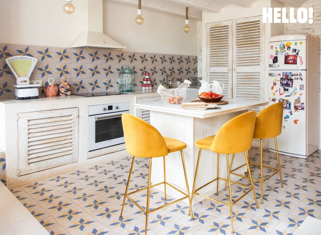 The kitchen with bright yellow breakfast stools and white, blue tiled floors in Macarena Gómez and Aldo Comas' house