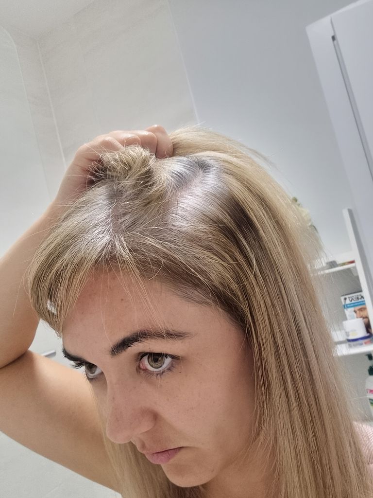 woman holding hair looking at grey roots